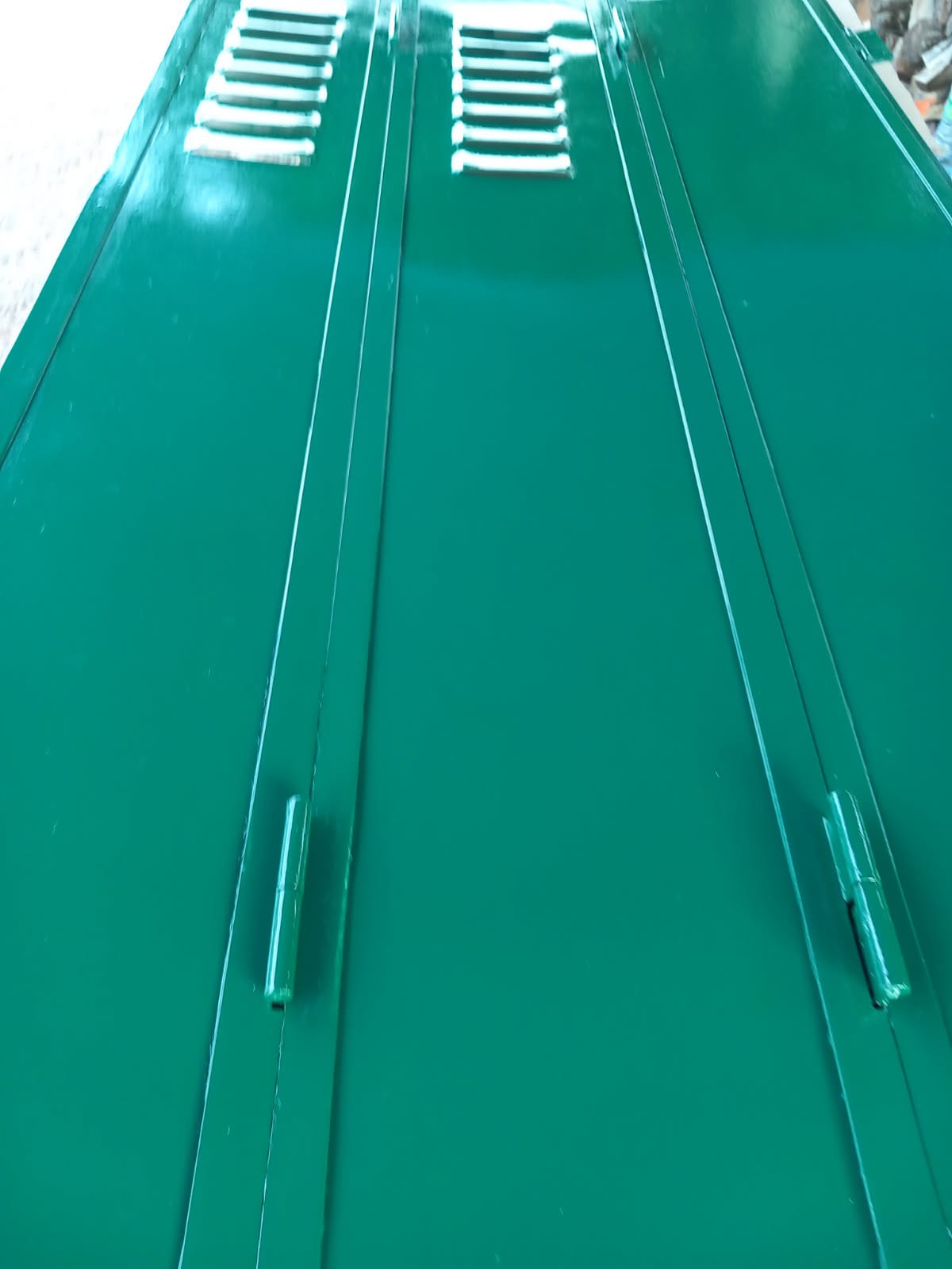 volet après Entreprise BAUD Close up of a glossy green metal surface with two parallel recessed grooves and small rectangular latches